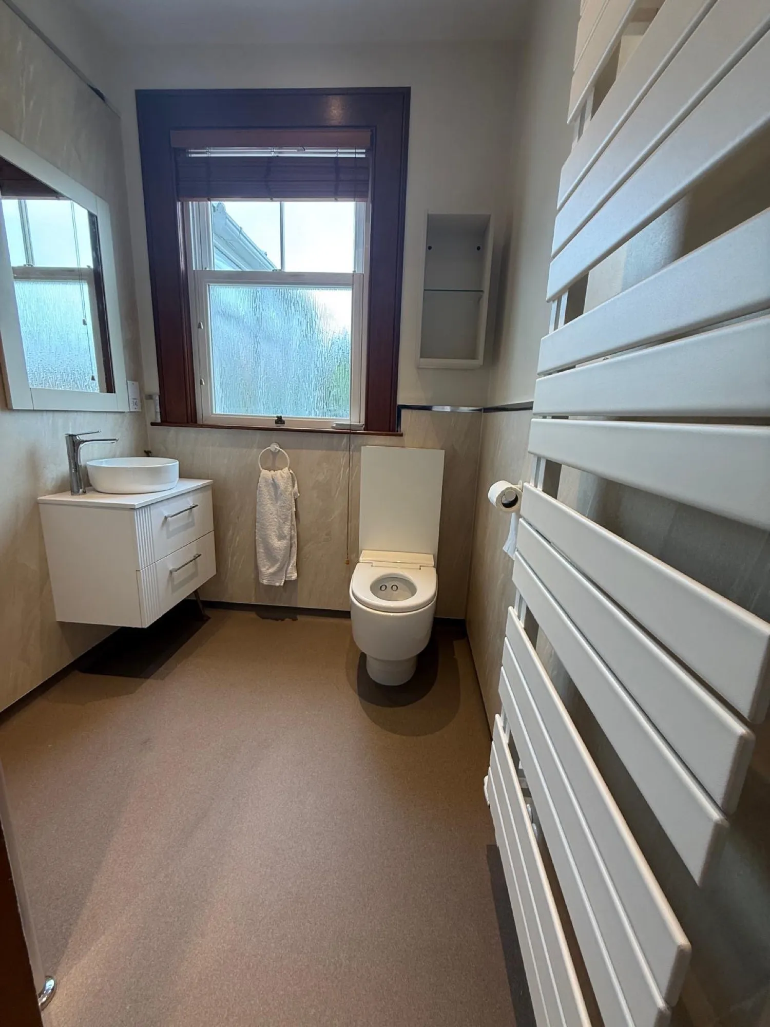 Towel radiator and vanity basin beside the window in a finished shower room