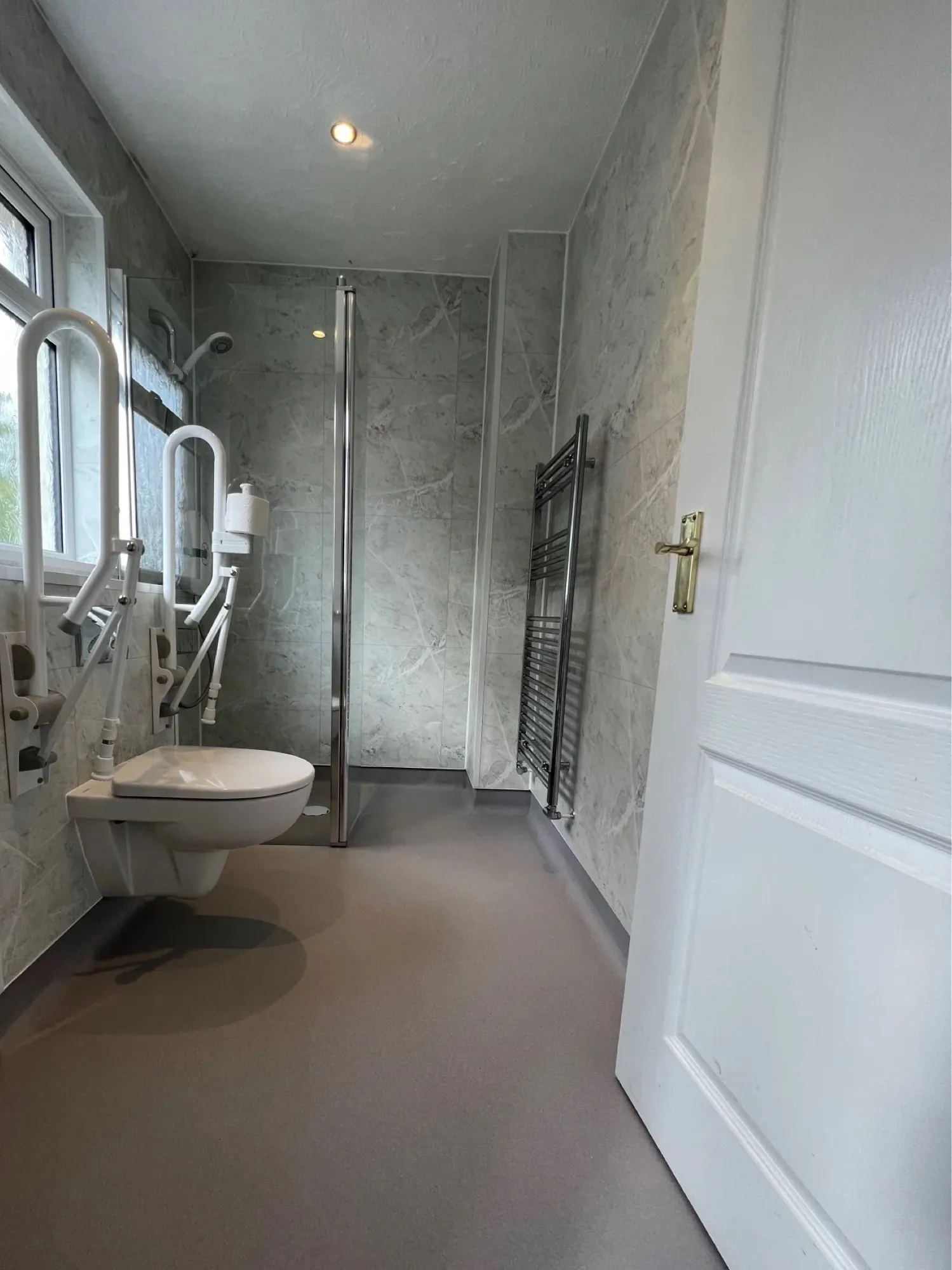 Marble-effect shower area with a chrome towel rail after a bath-to-shower conversion
