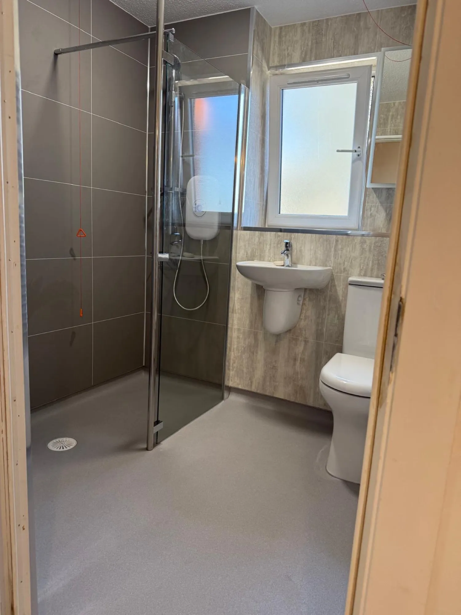 Grey shower enclosure beside the toilet and frosted window