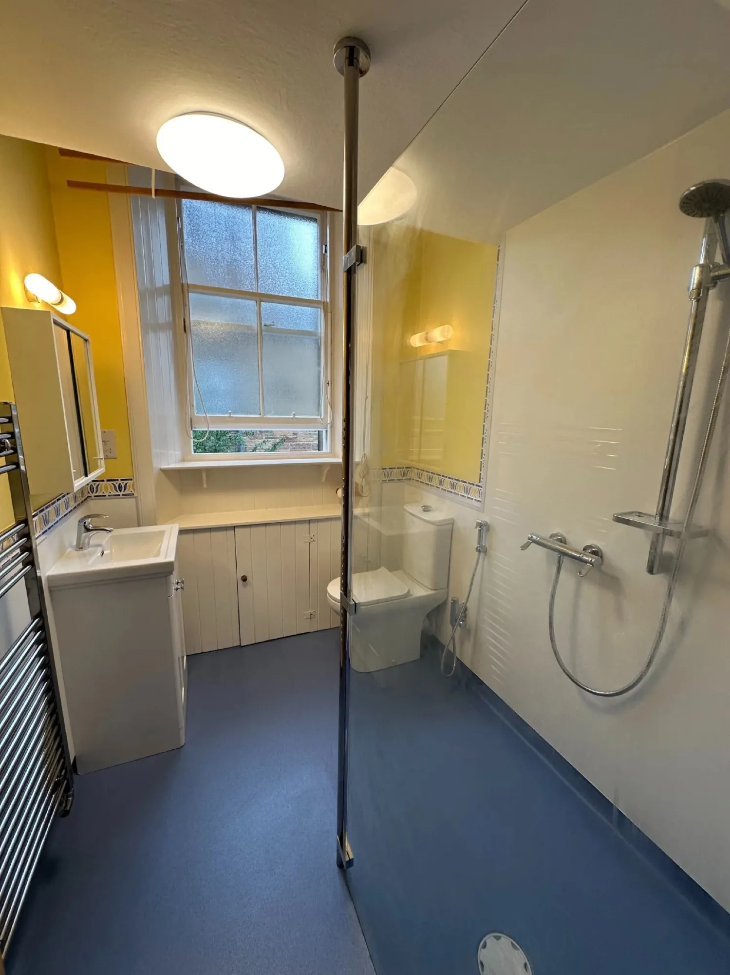 Bathroom with yellow walls and blue slip-resistant flooring after conversion