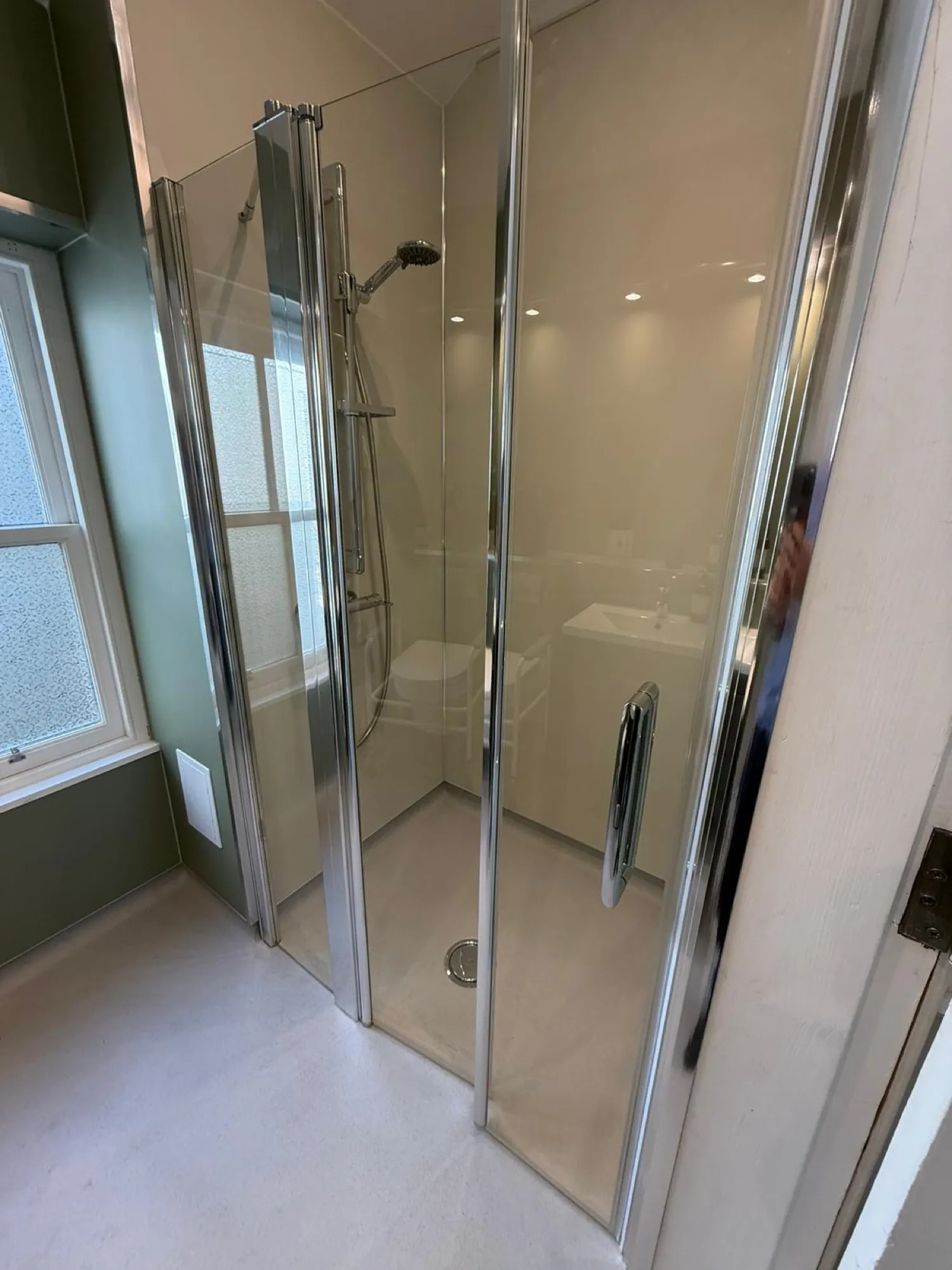 Glass shower enclosure in a green-toned bathroom