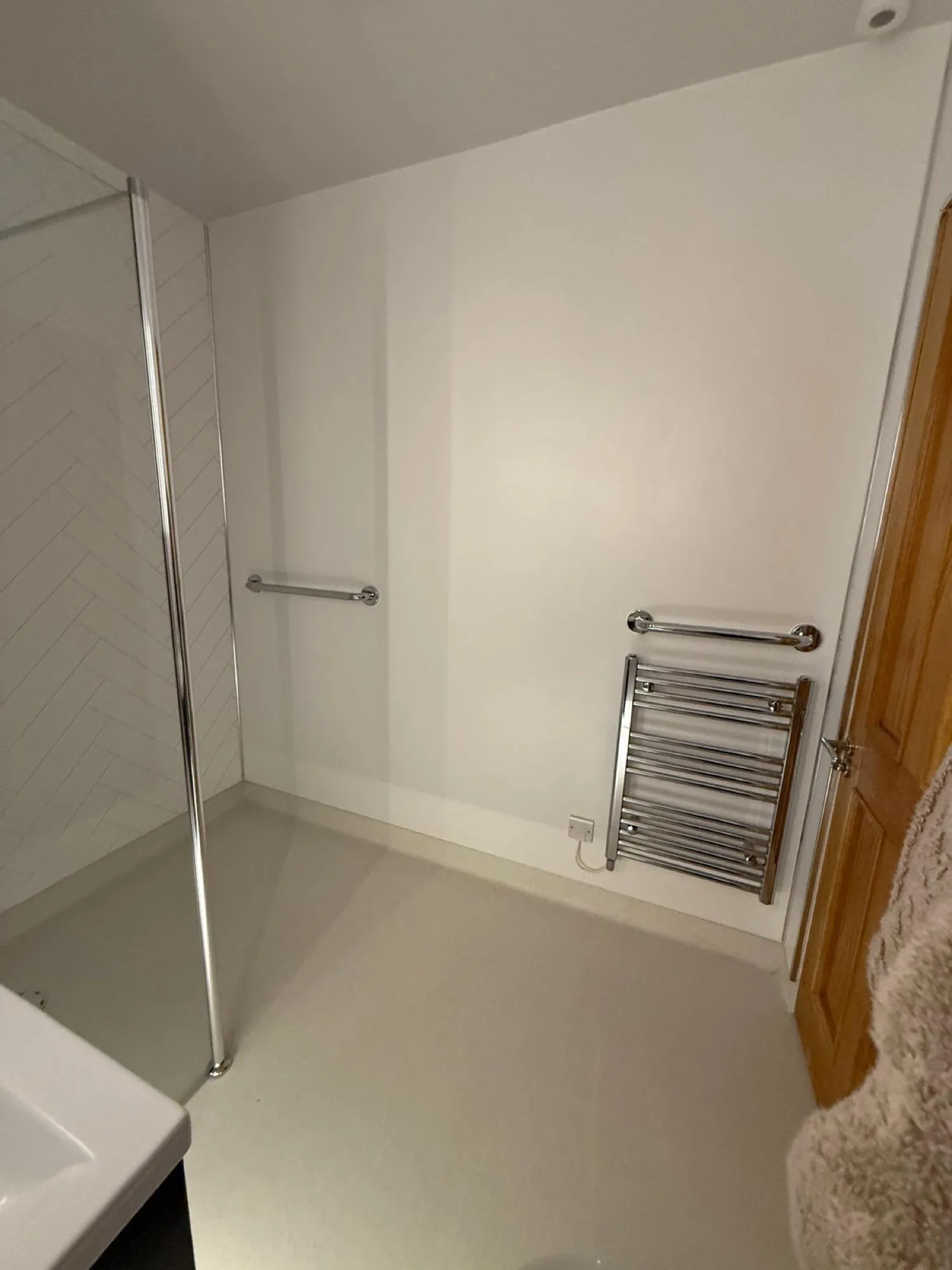 Low-profile shower tray with a chrome towel radiator