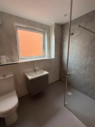 A finished level-access shower room with warm window light
