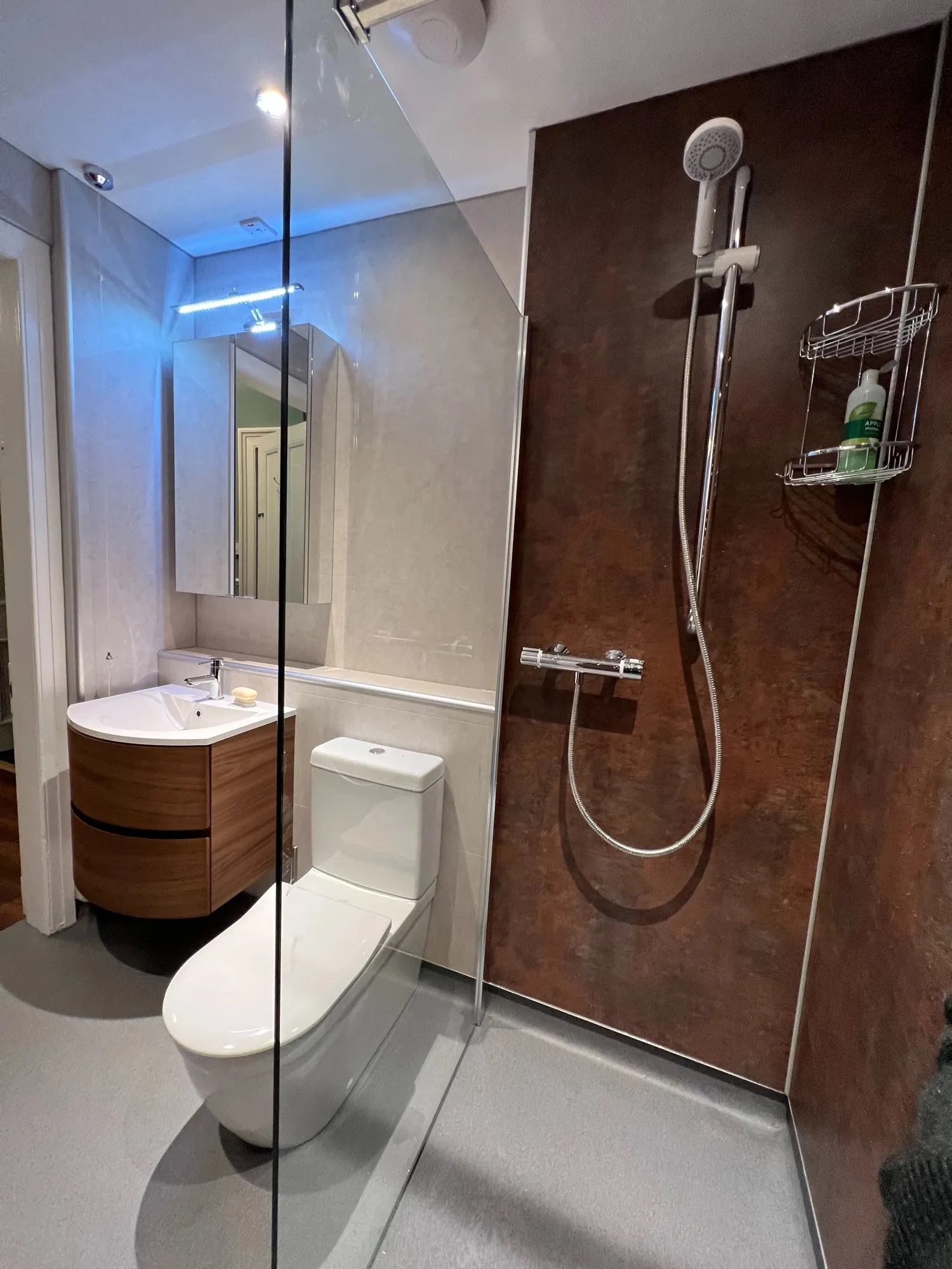 Wet room with copper-toned panels and a curved vanity unit