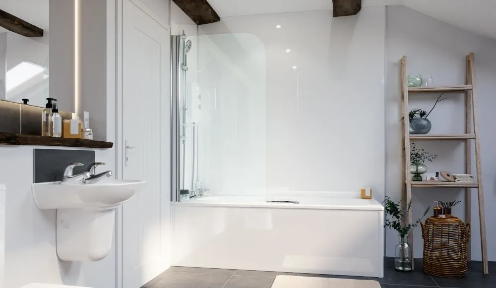 A full-length bath with a curved glass shower screen
