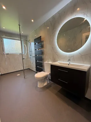 A completed accessible bathroom with marble-effect panelling