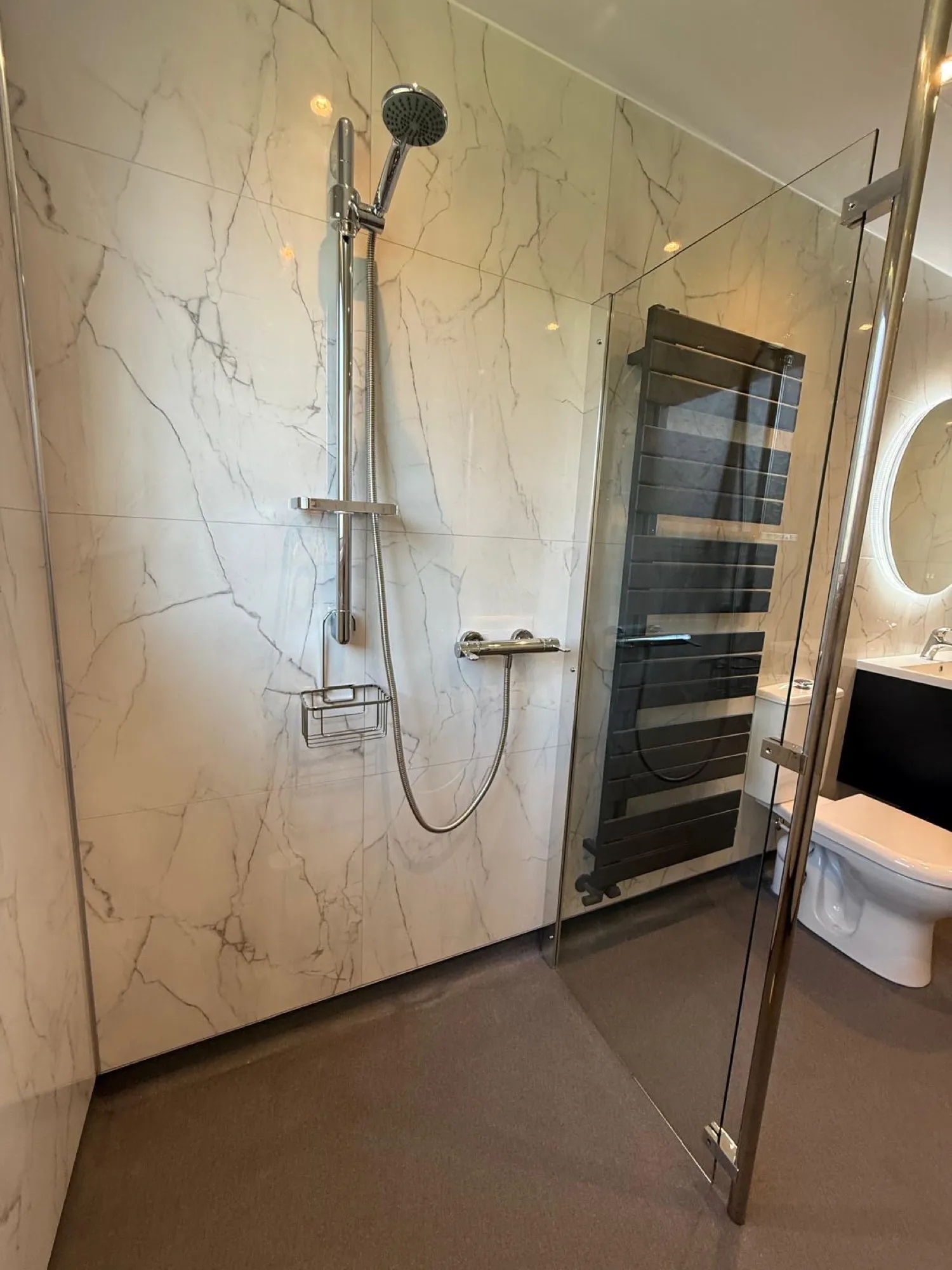 Marble-effect shower with a black towel radiator