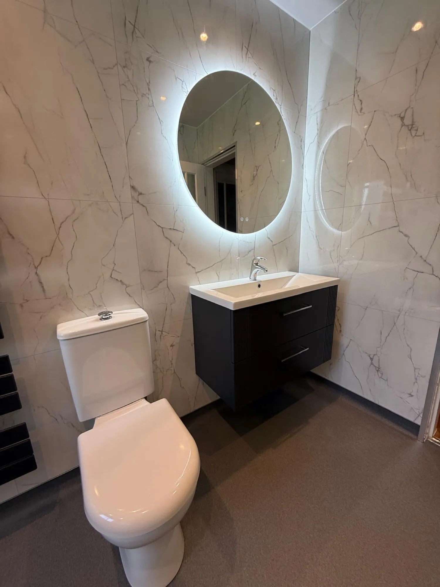 Illuminated mirror above the toilet and vanity in a finished bathroom