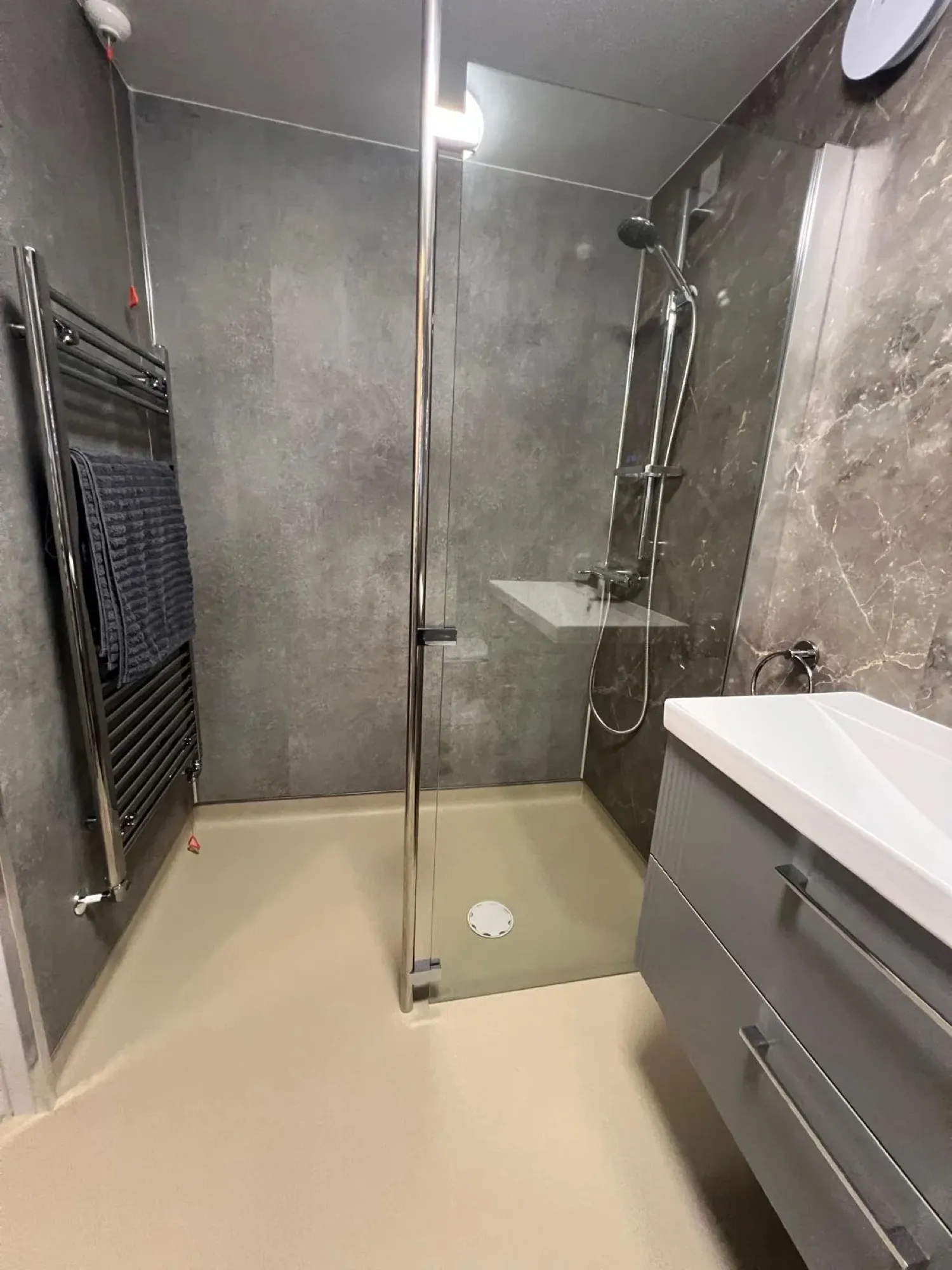 Walk-in shower with grey panels and a glass screen