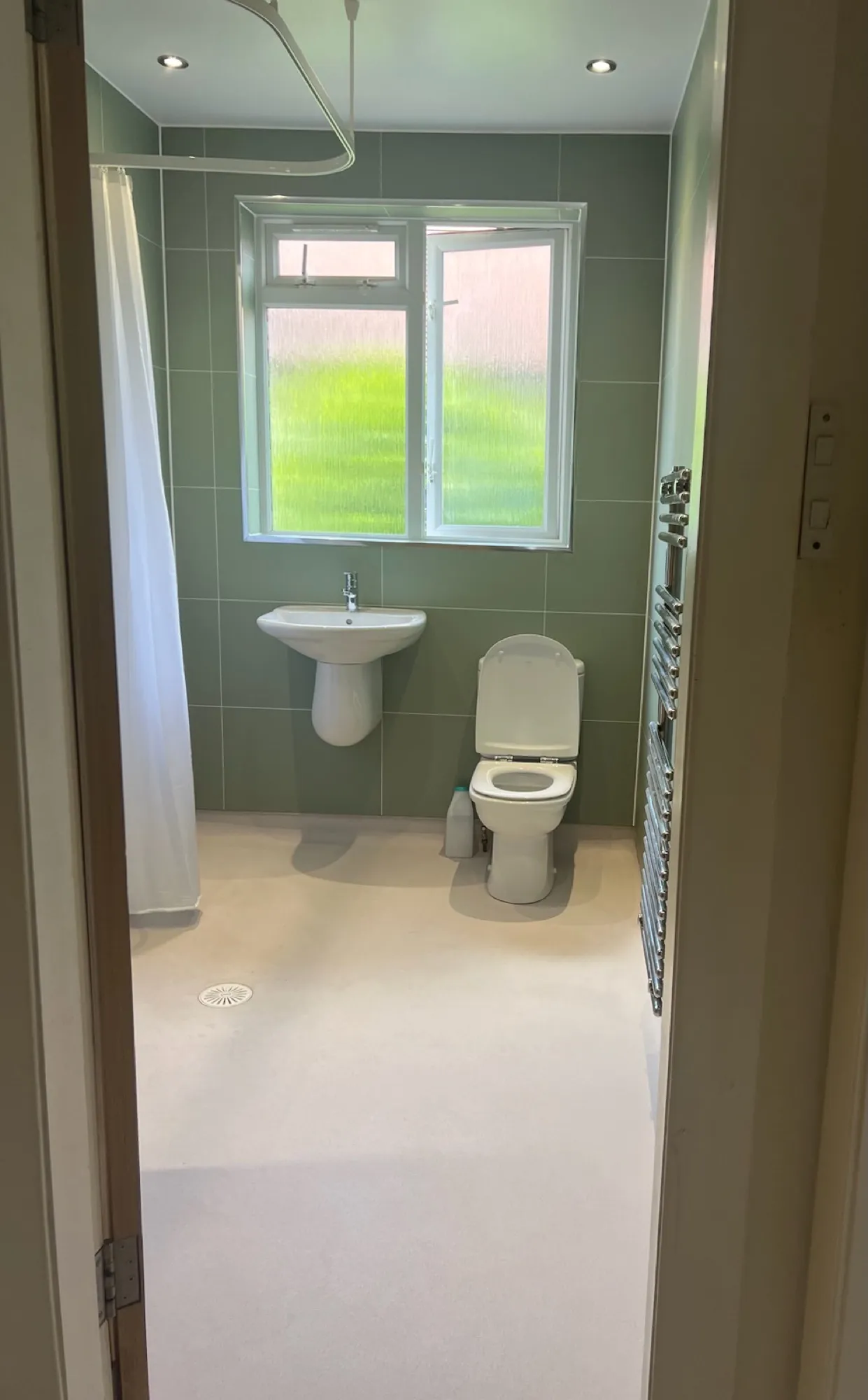 Green-toned bathroom with a wall-hung basin and toilet