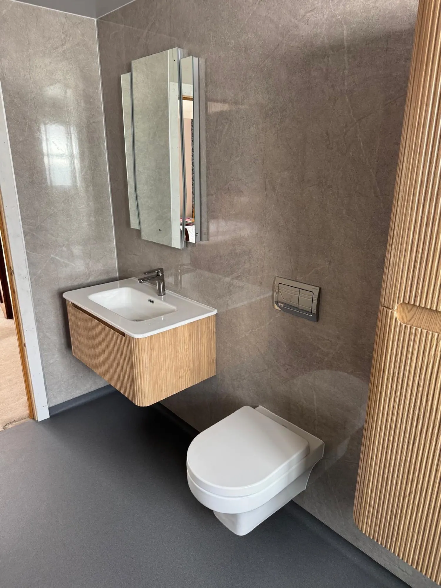 Wall-hung toilet beside wood-slat panelling