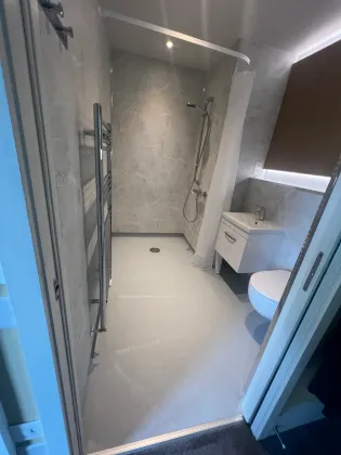 A finished walk-in shower room with stone-effect panels