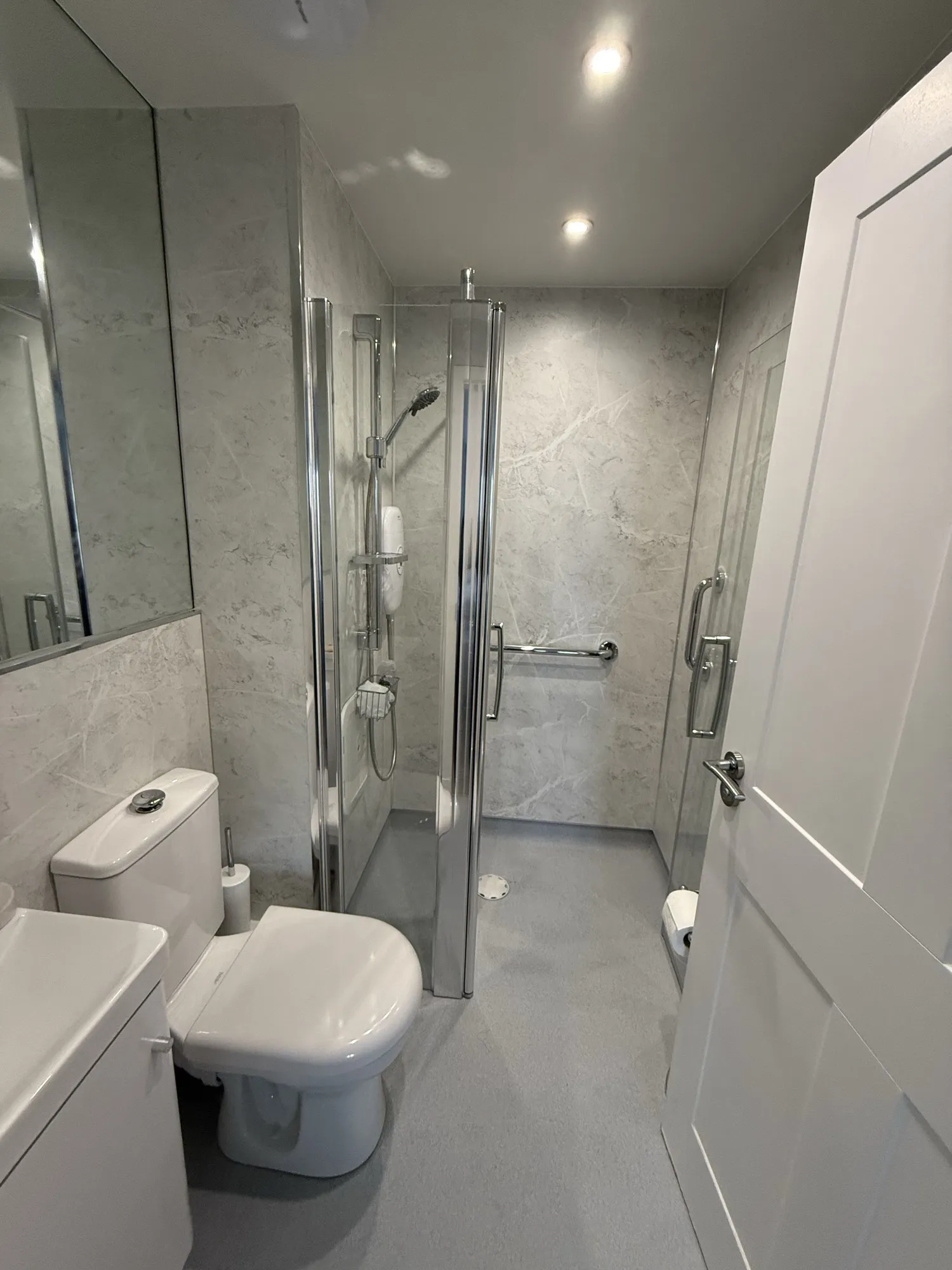 Shower room with marble-effect panels, toilet and glass screen