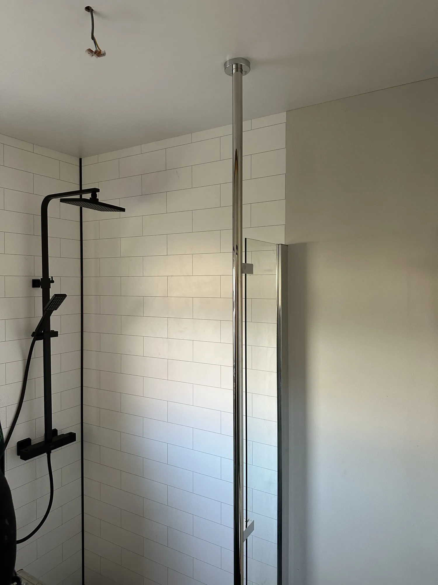 Black thermostatic shower against white tiled panels
