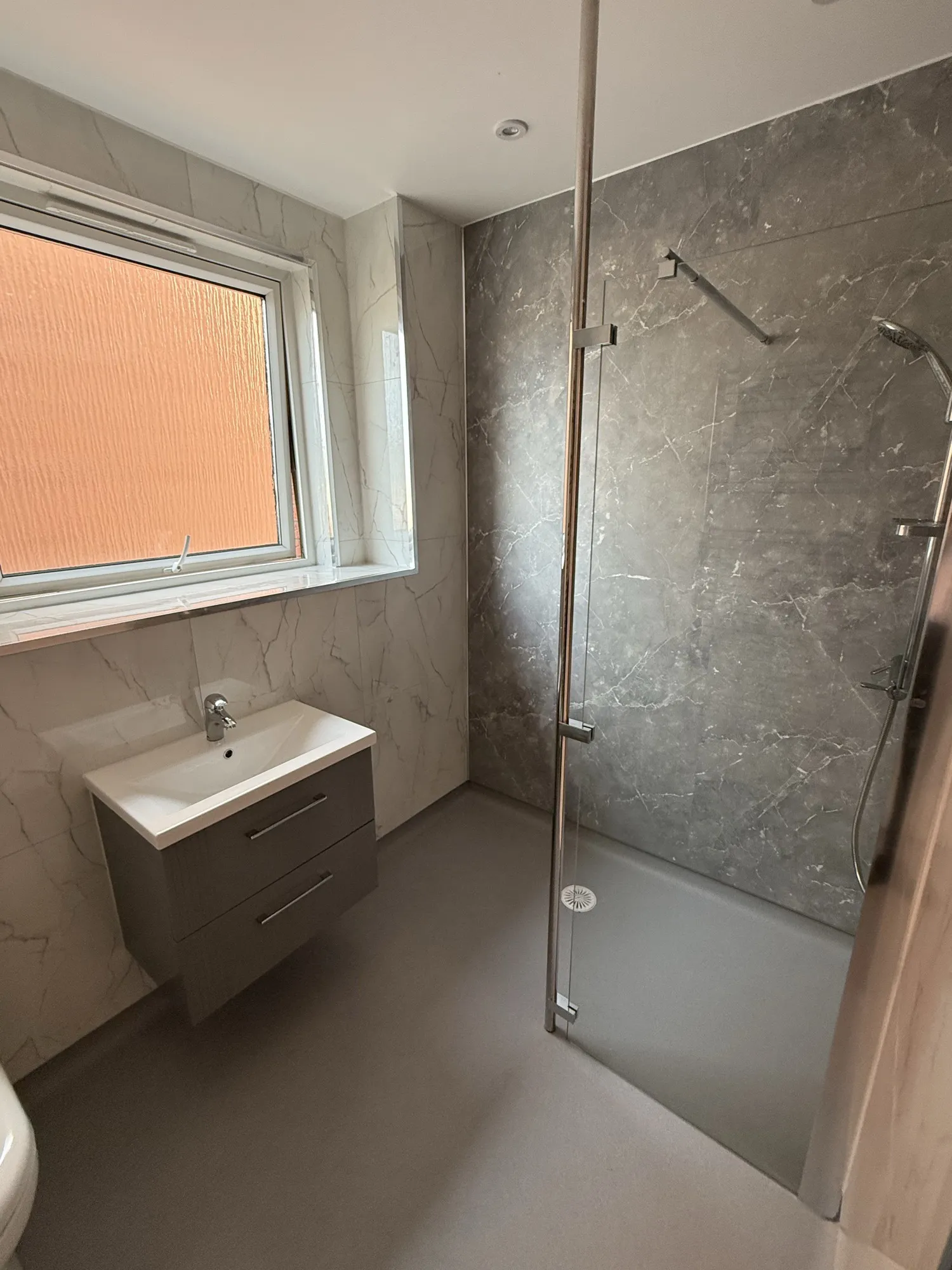 Vanity basin and walk-in shower with stone-effect panelling