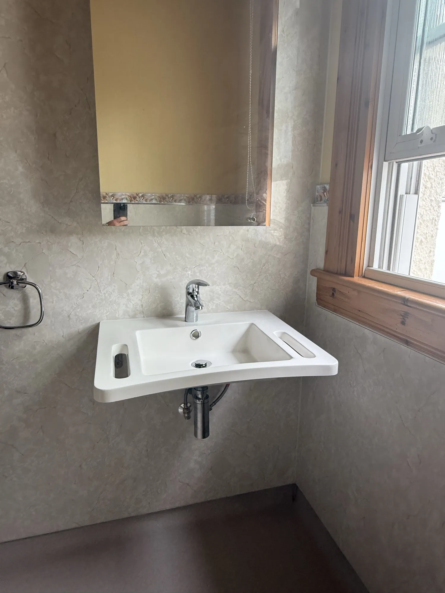 Wall-hung basin beneath a window in a finished bathroom