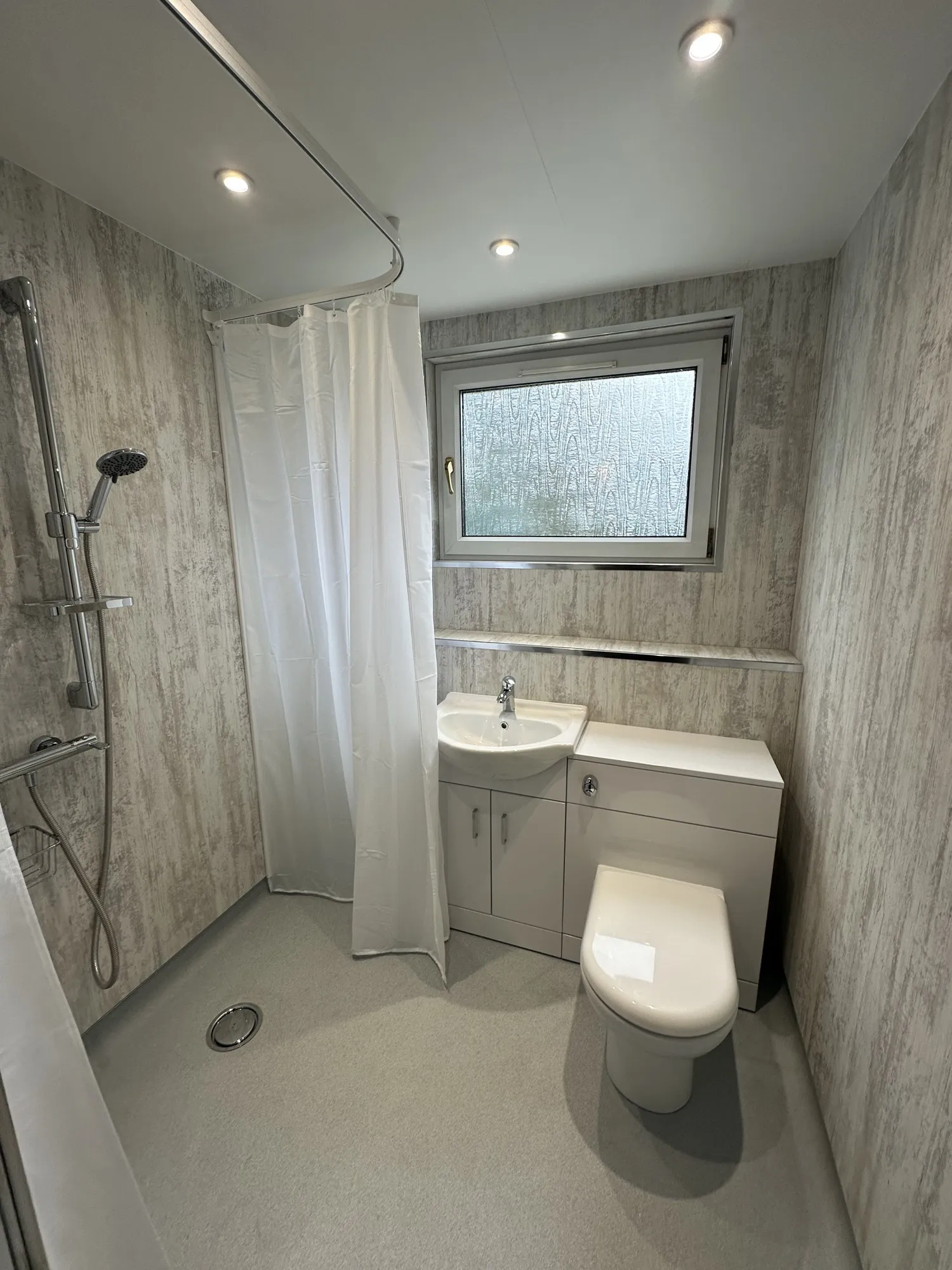 Wet room with a shower curtain and grey wall panels