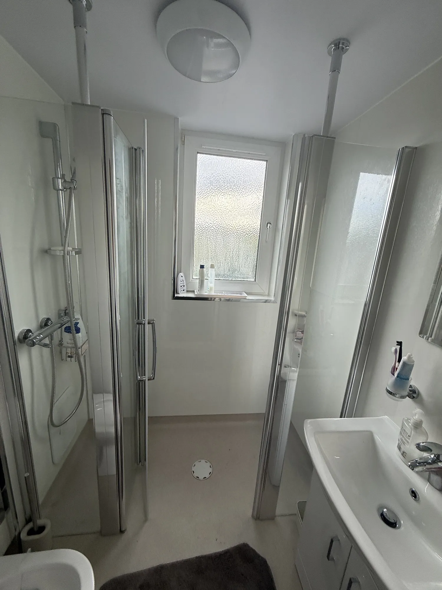 Walk-in shower beside a window and basin
