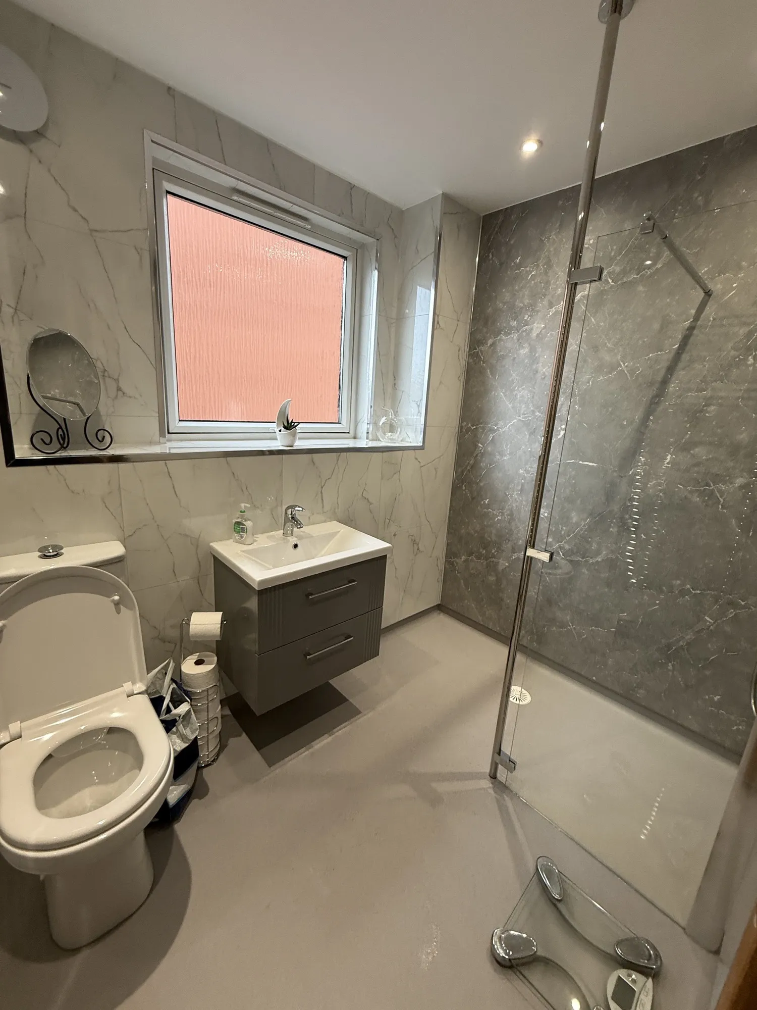Marble-effect shower room with a grey vanity and frosted window