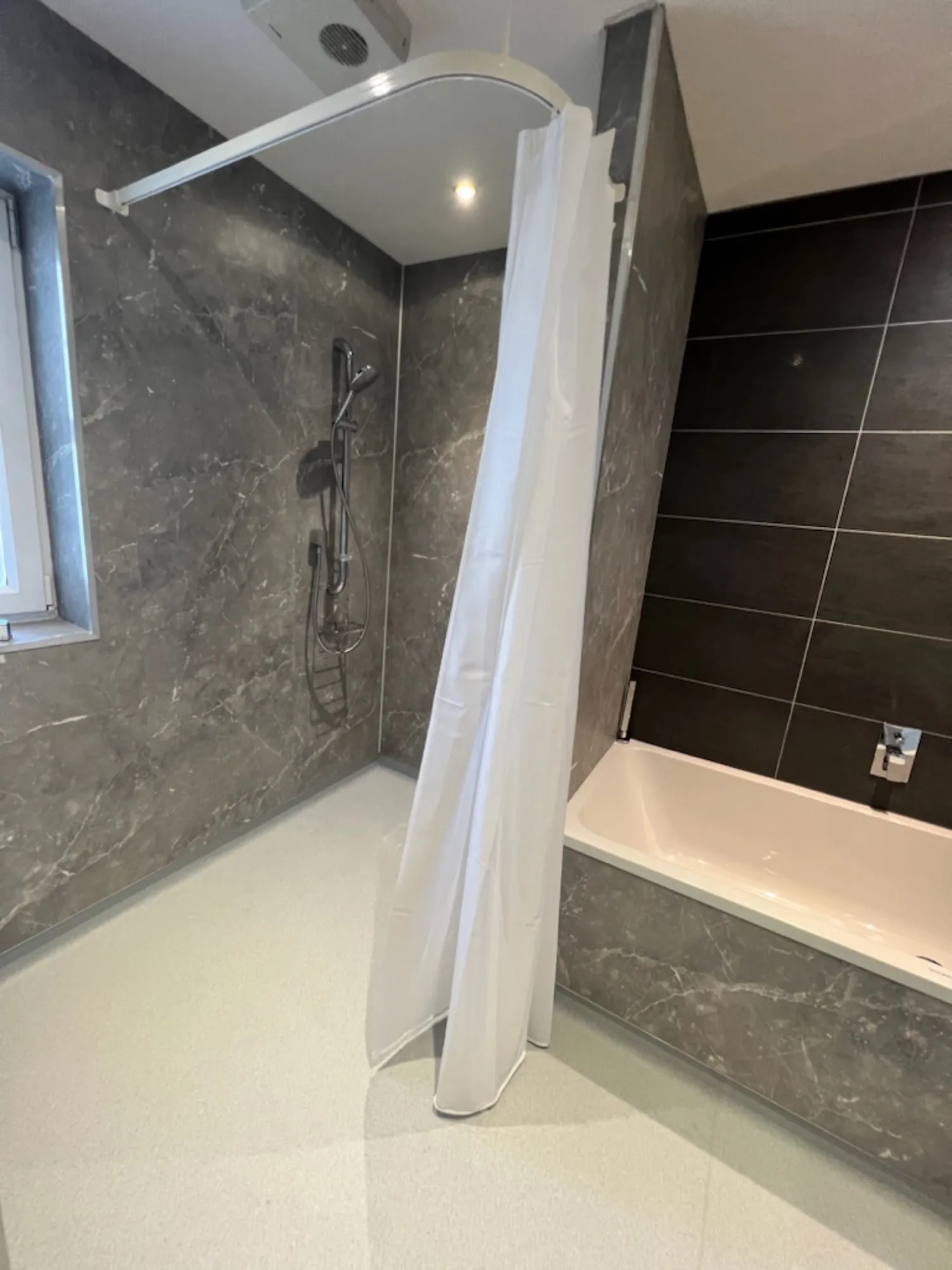 Round mirror, black towel radiator and basin against white herringbone panels