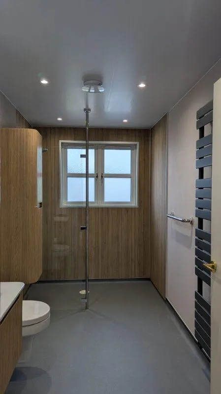 A level-access wet room with wood-effect wall panels