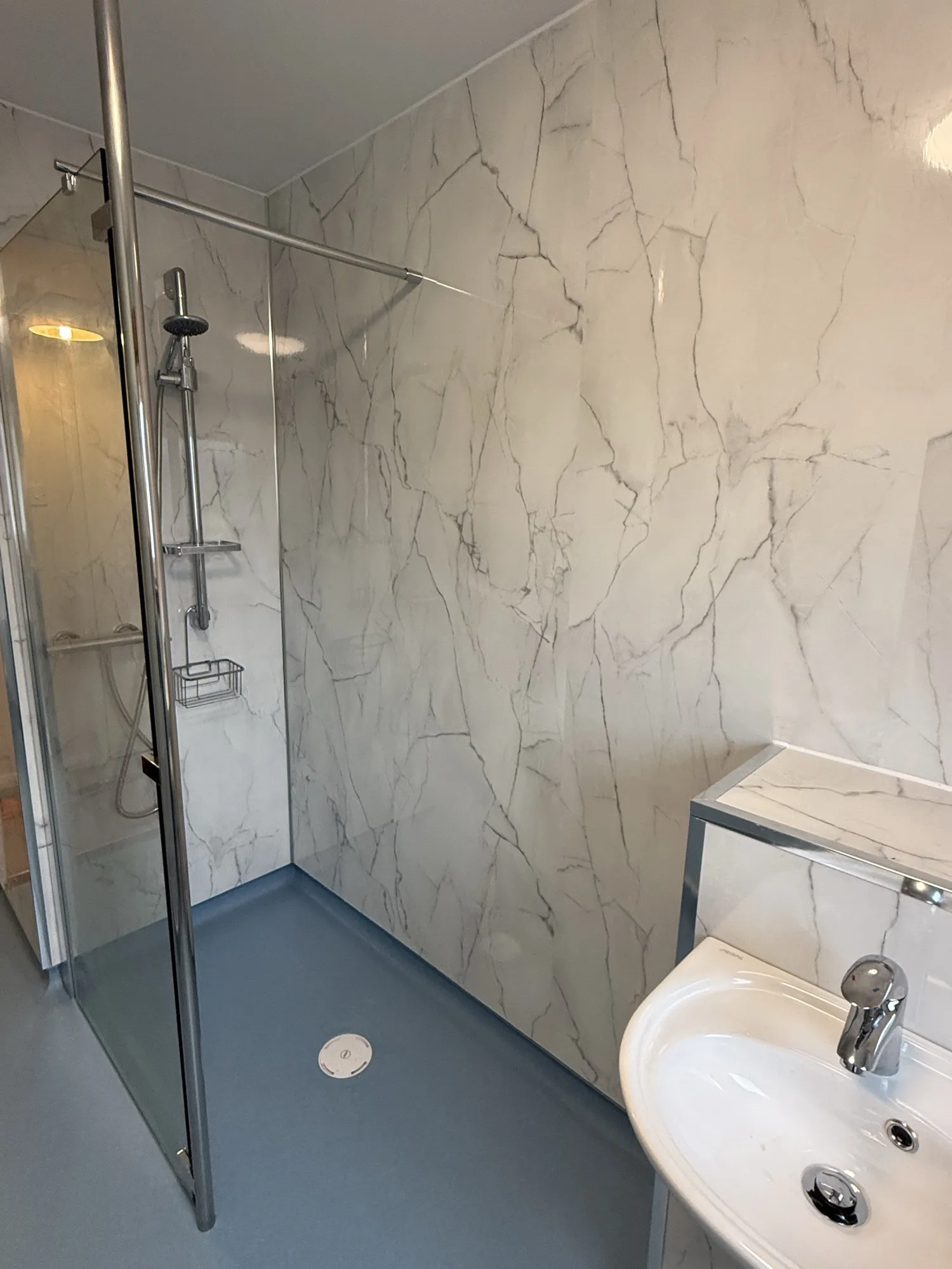 White bath and vanity against dark tiled walls