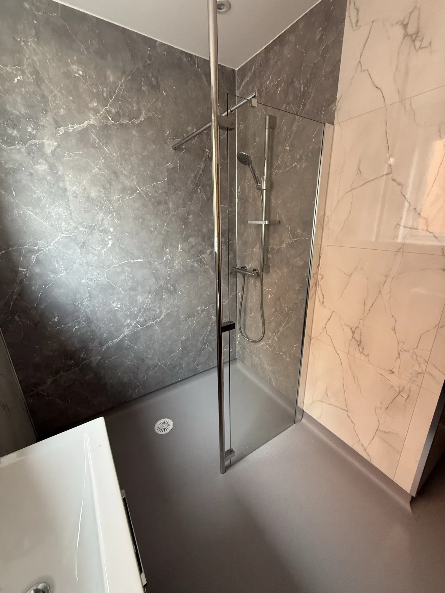 Walk-in shower with white marble-effect panels and a basin