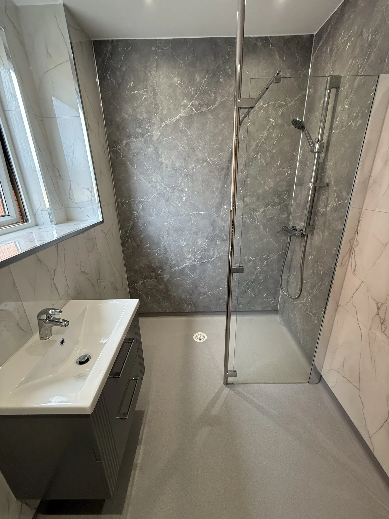 Marble-effect shower room with a vanity unit beneath the window