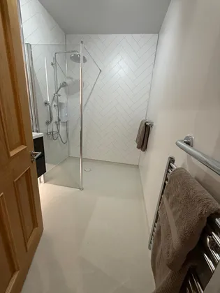 A completed bathroom with a low-profile shower tray and herringbone panelling