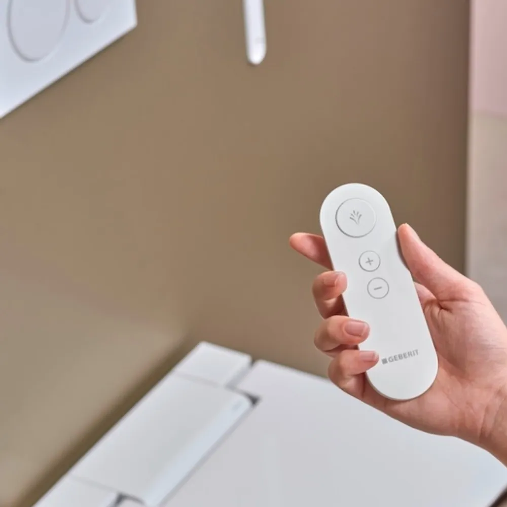 A hand holding the control for a wash-and-dry toilet